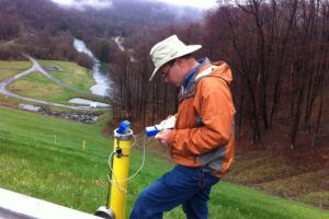 Man using Well Sounder water level sensor to monitor piezometer tube at landfill